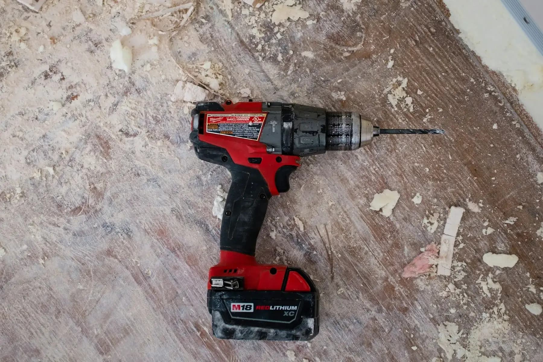 Cordless drill on a dusty timber floor during carpentry work