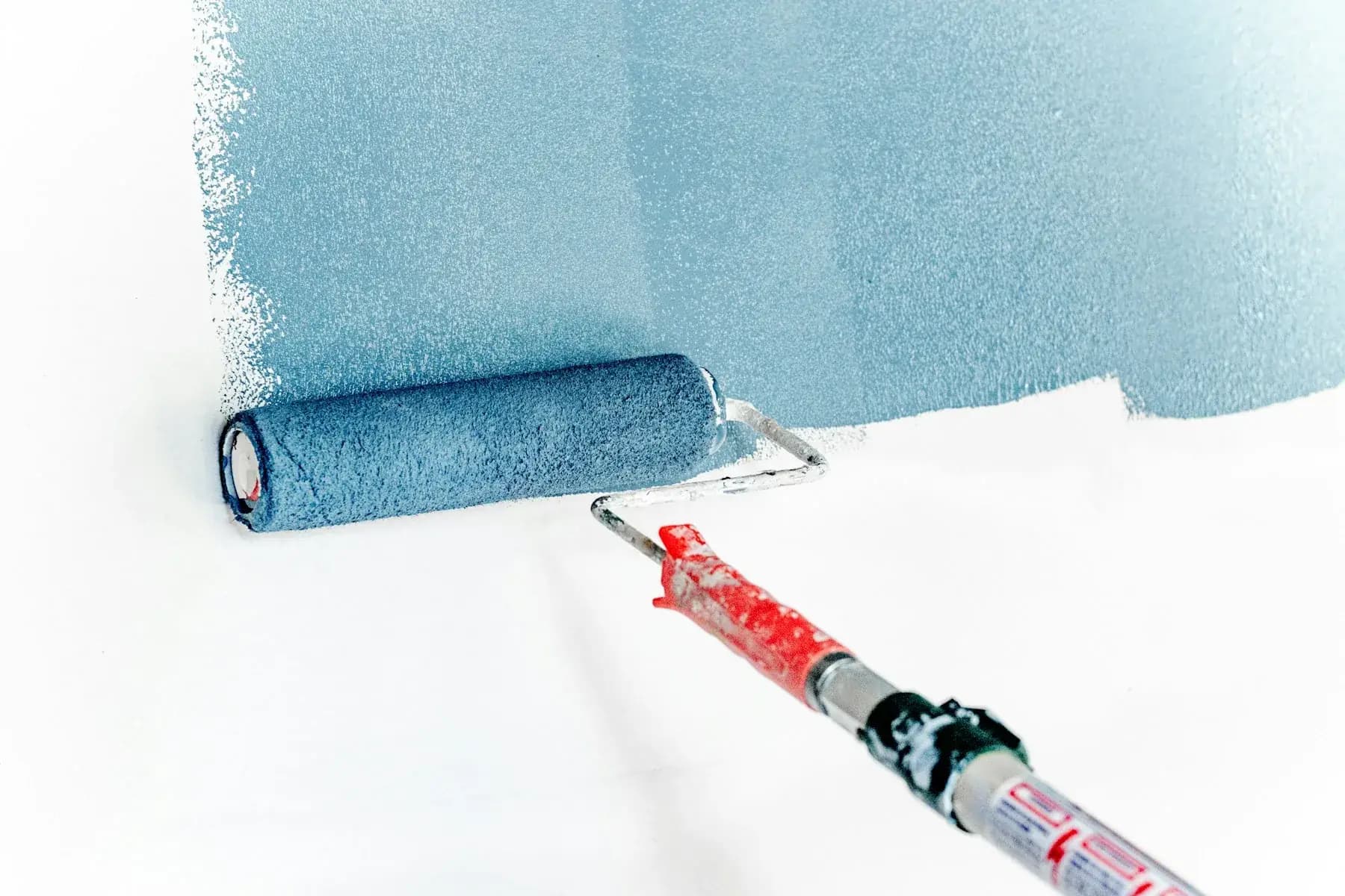Paint roller applying a fresh coat of blue paint to an interior wall